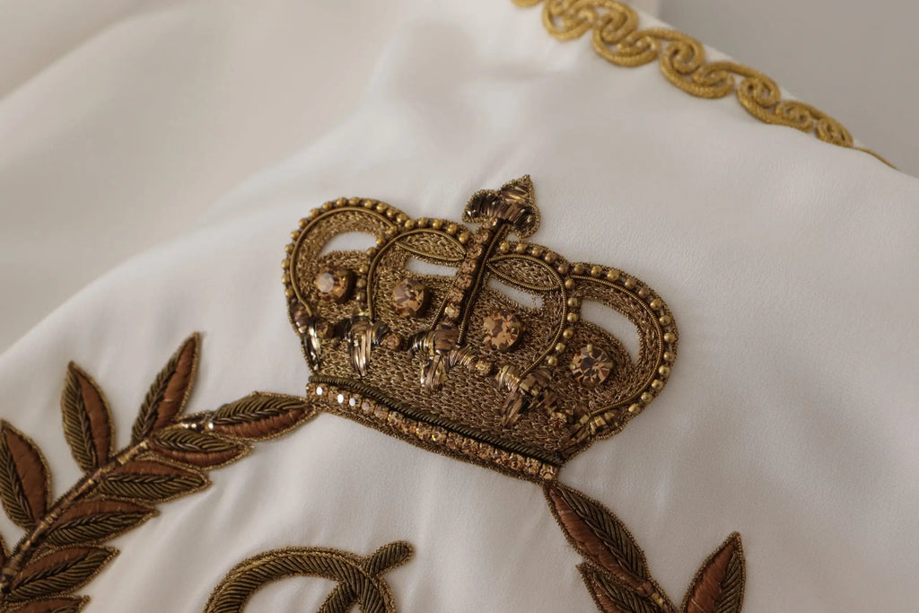 Détail d’une blouse blanche en soie dolce & gabbana avec couronne dorée brodée de cristaux et perles fines