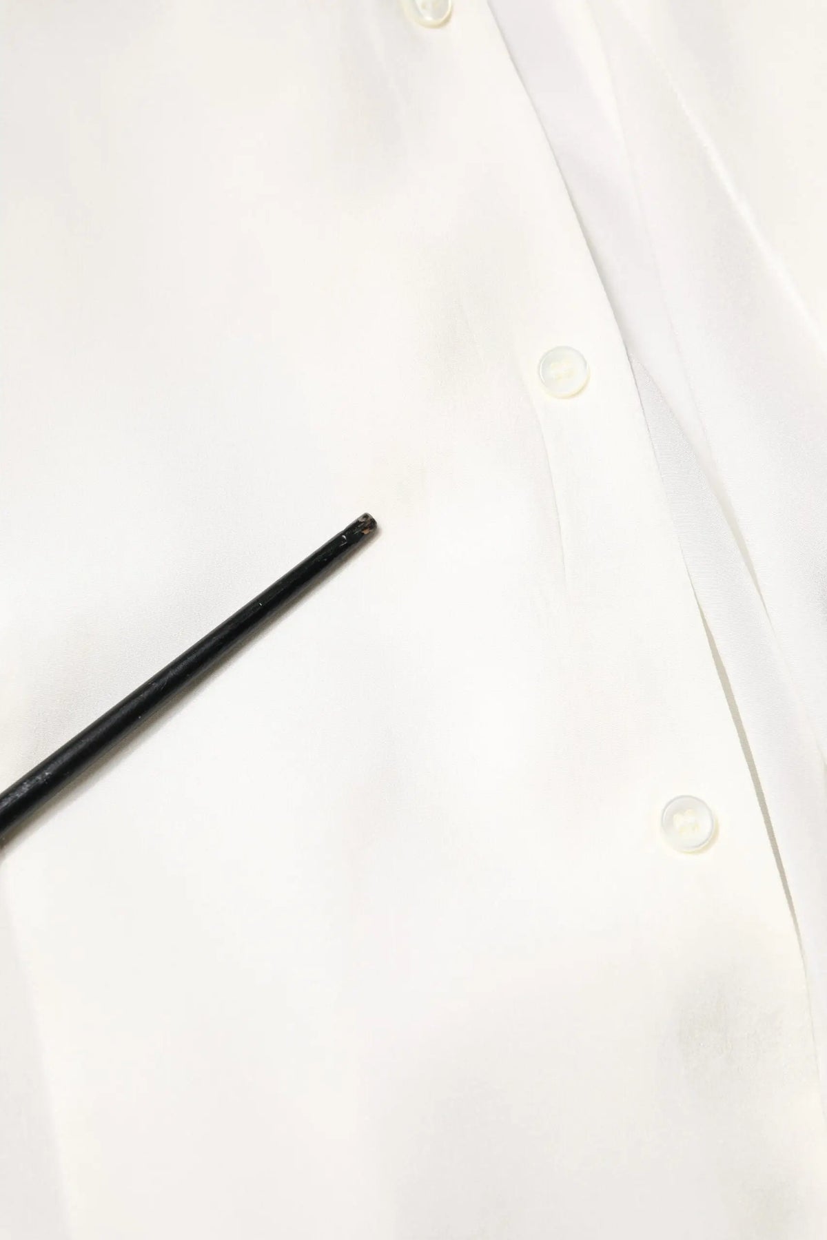 Stylo noir cylindrique posé sur une chemise formelle blanche en soie Dolce & Gabbana à col classique en or