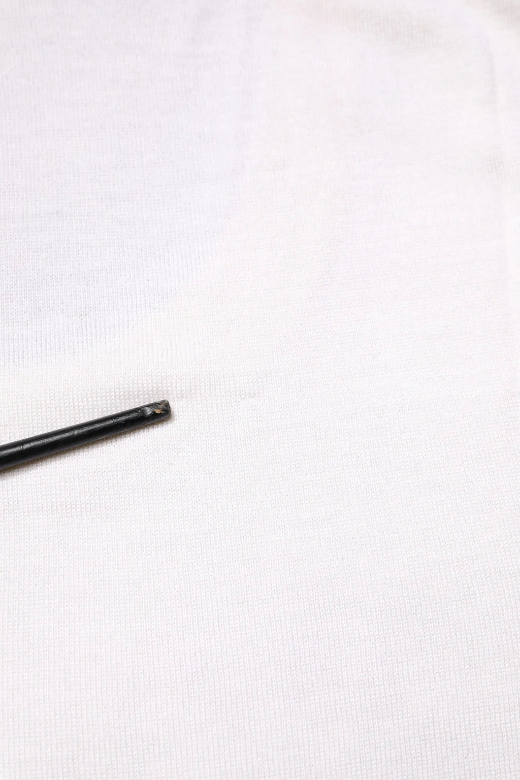 Objet cylindrique noir avec extrémité usée et texturée lié au débardeur en cachemire blanc sans manches dolce & gabbana