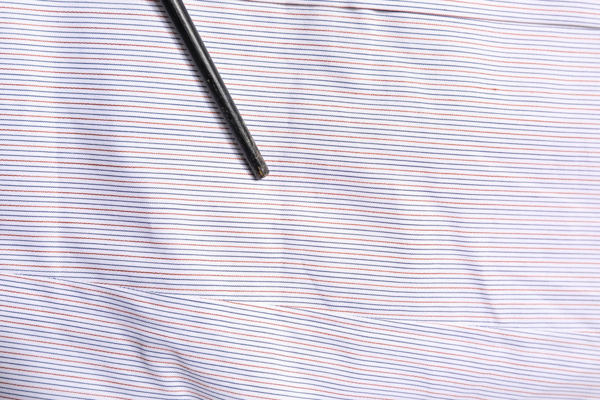 Une chemise dolce & gabbana blanche à fines rayures rouges et bleues en coton avec manches longues et un crayon noir dessus