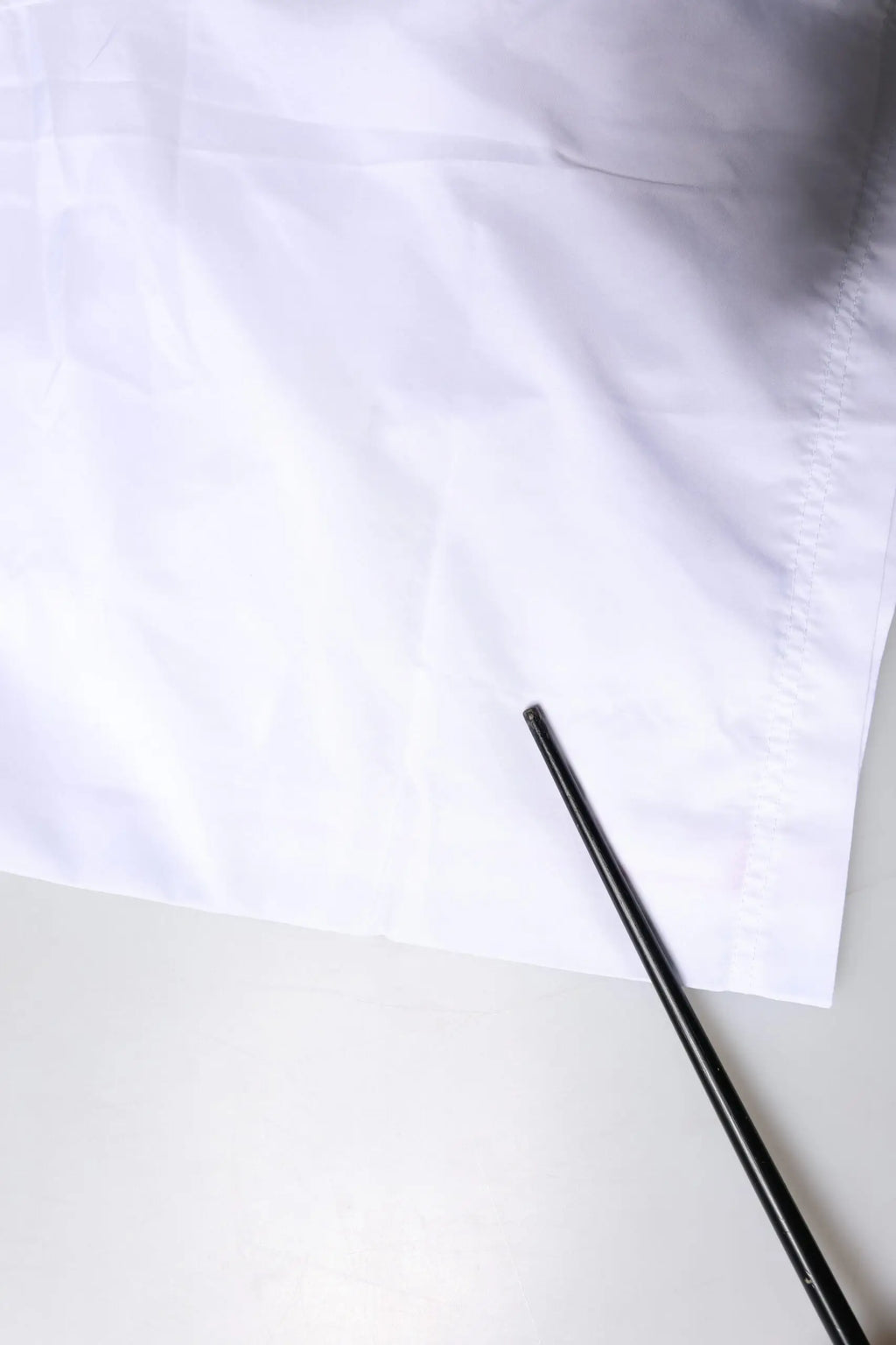 Chopsticks en métal noir posés sur un tissu blanc avec short de bain dolce et gabbana rayures blanches 2 pièces