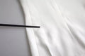 Un repose-baguettes noir élégant posé sur un tissu blanc lisse à côté d’un top blanc en viscose dolce & gabbana manches courtes