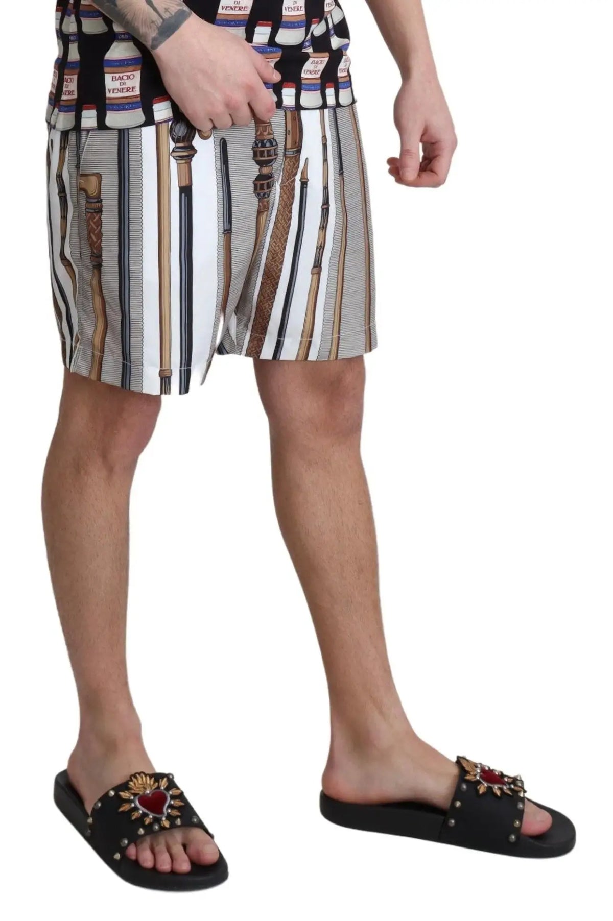 Black slide sandals with red heart and gold embellishments paired with dolce & gabbana white walking stick beachwear shorts