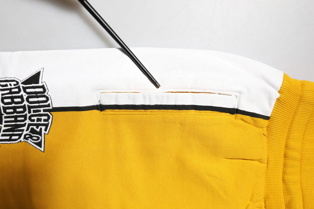 Veste universitaire jaune et blanche en coton avec bordure noire et patch graphique audacieux sur la manche dolce gabbana