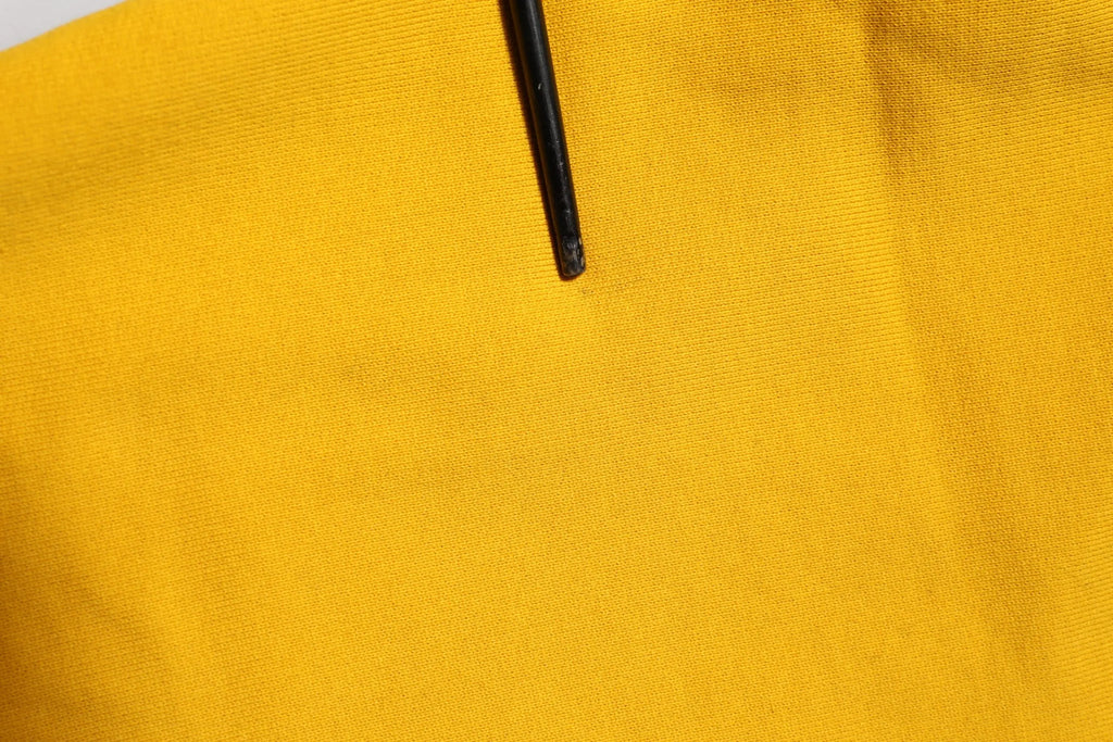 Un tirette de fermeture éclair noir repose sur un tissu jaune vif des joggers en coton avec logo dolce & gabbana