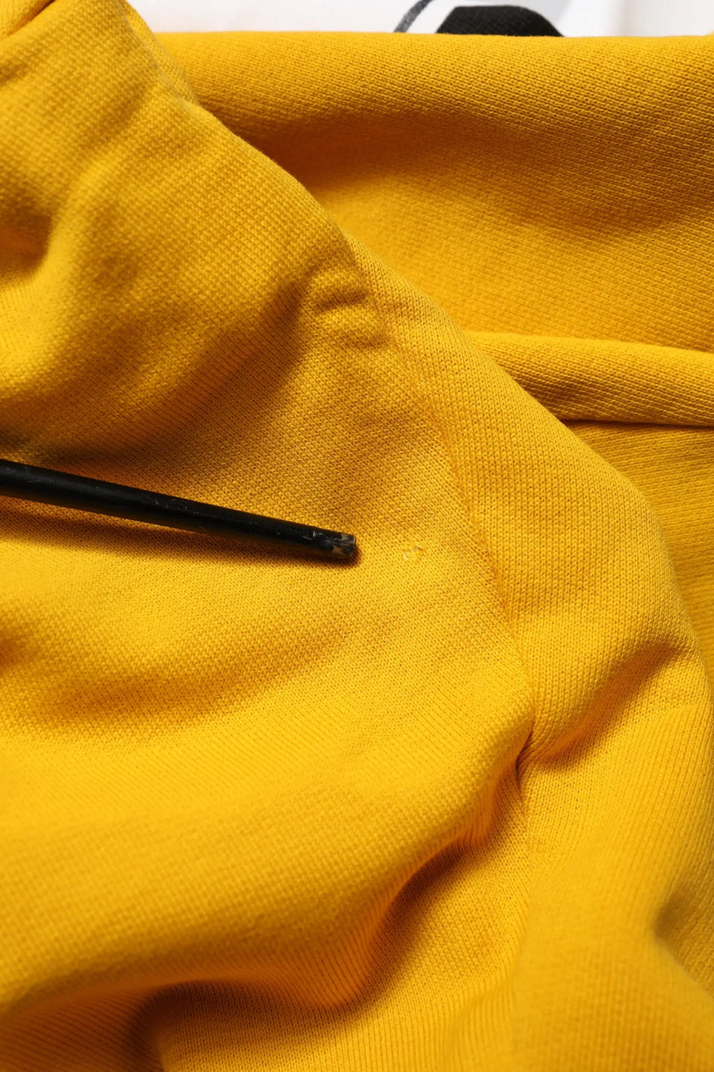 Une baguette noire repose sur un tissu en maille jaune moutarde des pantalons jogger en coton dolce & gabbana