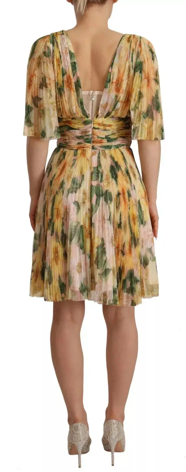 Une femme porte une robe midi plissée dolce & gabbana à imprimé floral jaune vert et rose doux