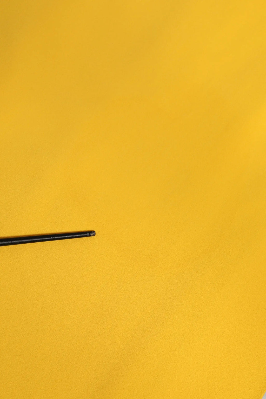 Chopstick noir posé sur une surface jaune vif avec robe midi jaune d et g avec épaule unique et fente