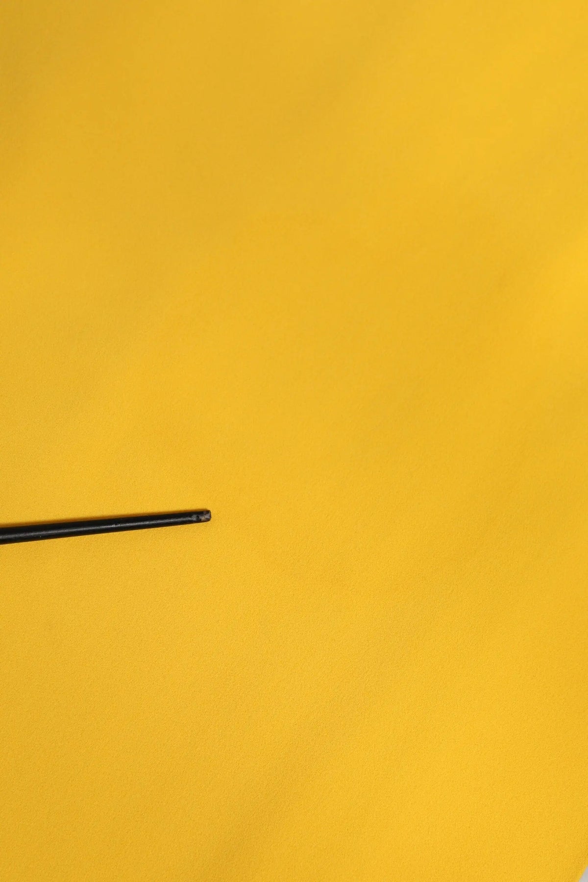 Chopstick noir posé sur une surface jaune vif avec robe midi jaune d et g avec épaule unique et fente