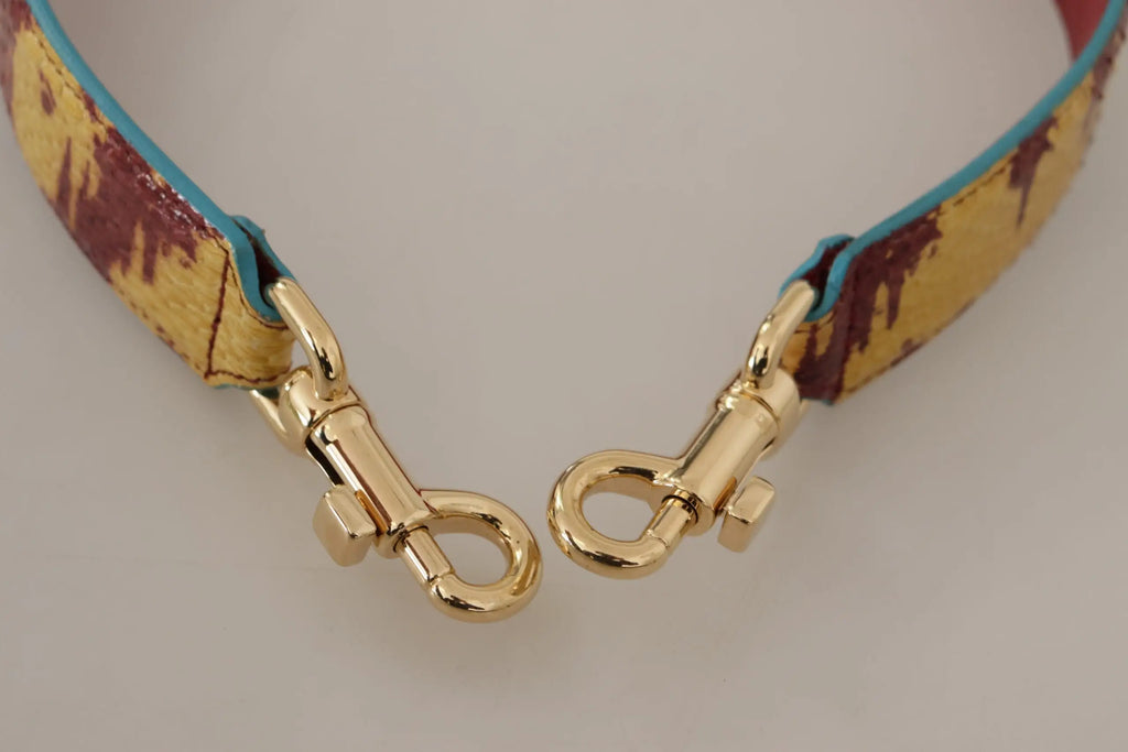 Gold tone metal clasps attach to a yellow and maroon paint splatter leather shoulder strap by dolce gabbana