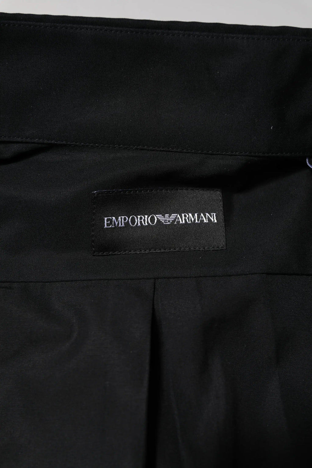 Étiquette noire emporio armani avec logo blanc brodé sur tissu noir pour chemise habillée homme coton manches longues