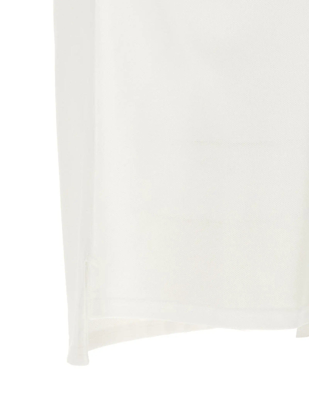Un polo Givenchy blanc en coton présenté derrière un rideau blanc transparent à plis verticaux subtils