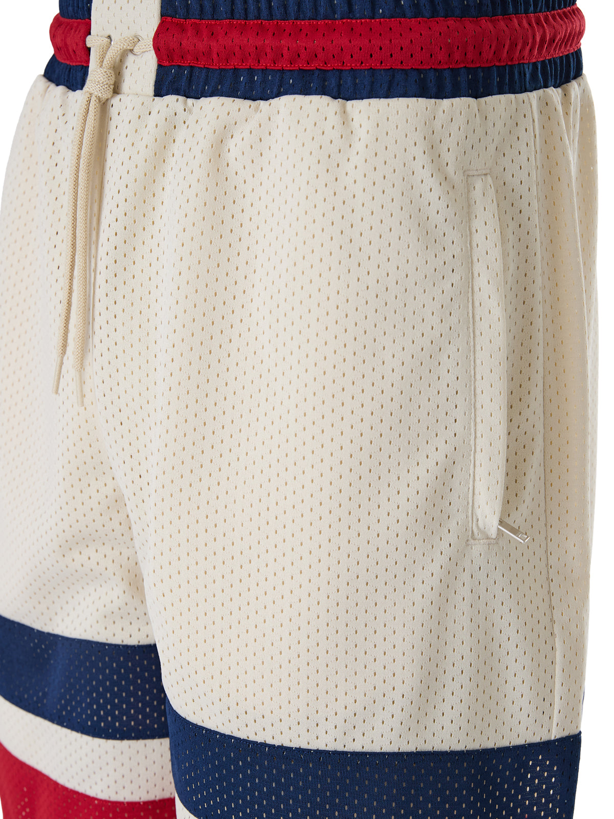 Shorts en polyester couleur crème avec logo Gucci, vêtement décontracté pour homme ou femme, visible en détail dans l'image.