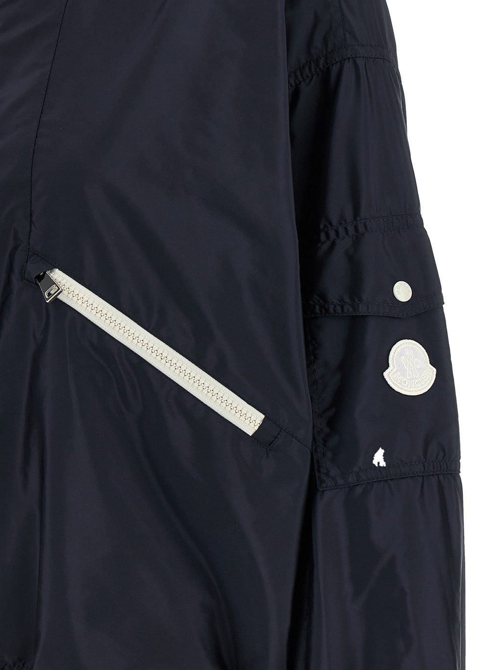 Veste Moncler en polyamide bleu, coupe-vent et légère, avec capuche et fermeture éclair visible.