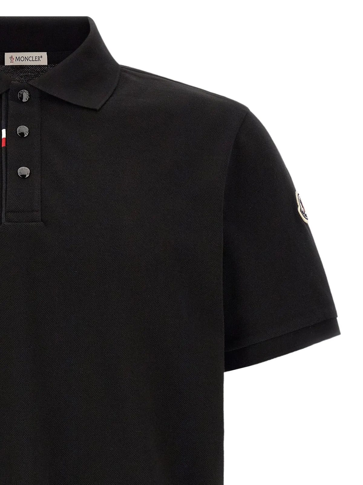Polo noir moncler en coton avec maille piquée texturée, patte de boutonnage à trois boutons argentés et logo sur la manche
