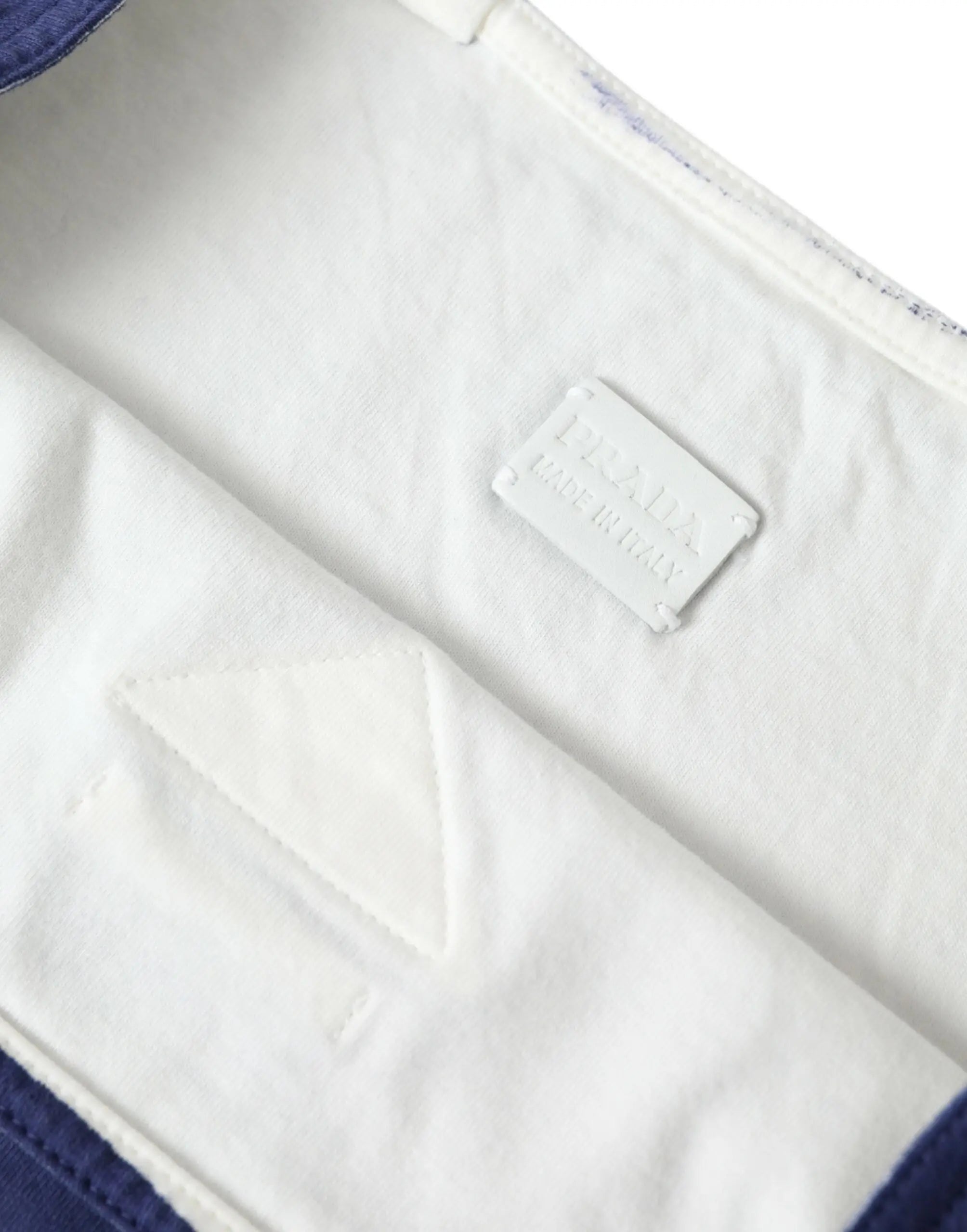 Étiquette blanche prada avec texte en relief et bords cousus sur intérieur en tissu du sac shopping en jersey bleu prada
