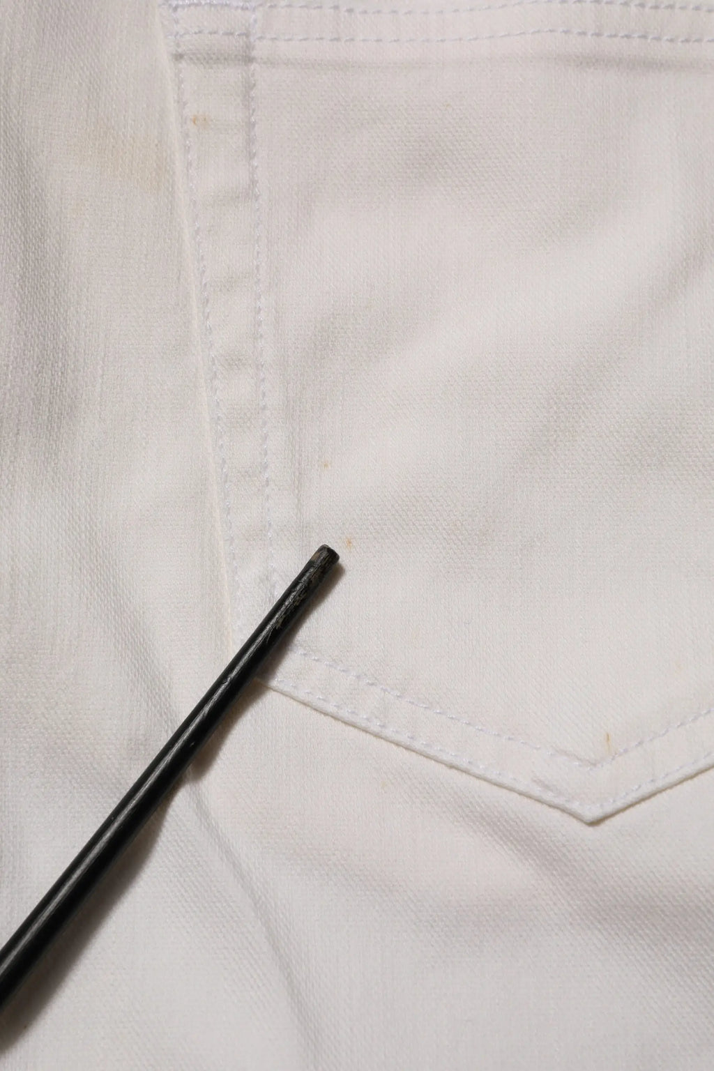 Stylo noir posé sur un jean blanc en denim prada taille mi-haute coupe skinny usage casual