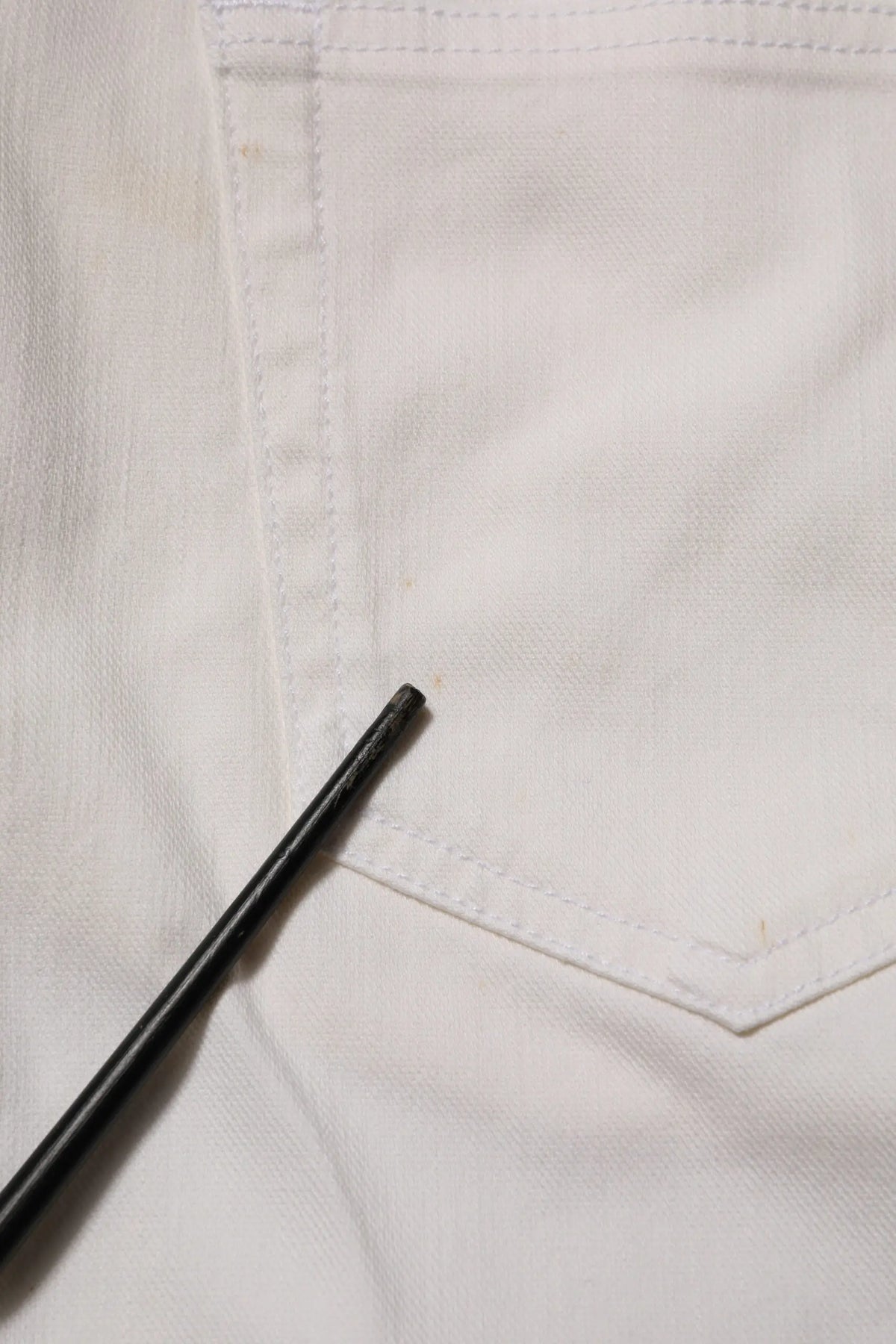 Stylo noir posé sur un jean blanc en denim prada taille mi-haute coupe skinny usage casual