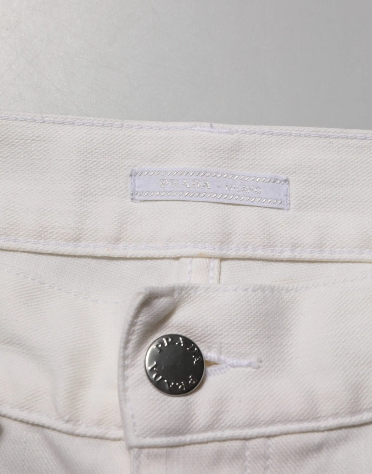 Jean blanc en denim prada taille mi-haute coupe skinny avec bouton argenté et étiquette de marque visible
