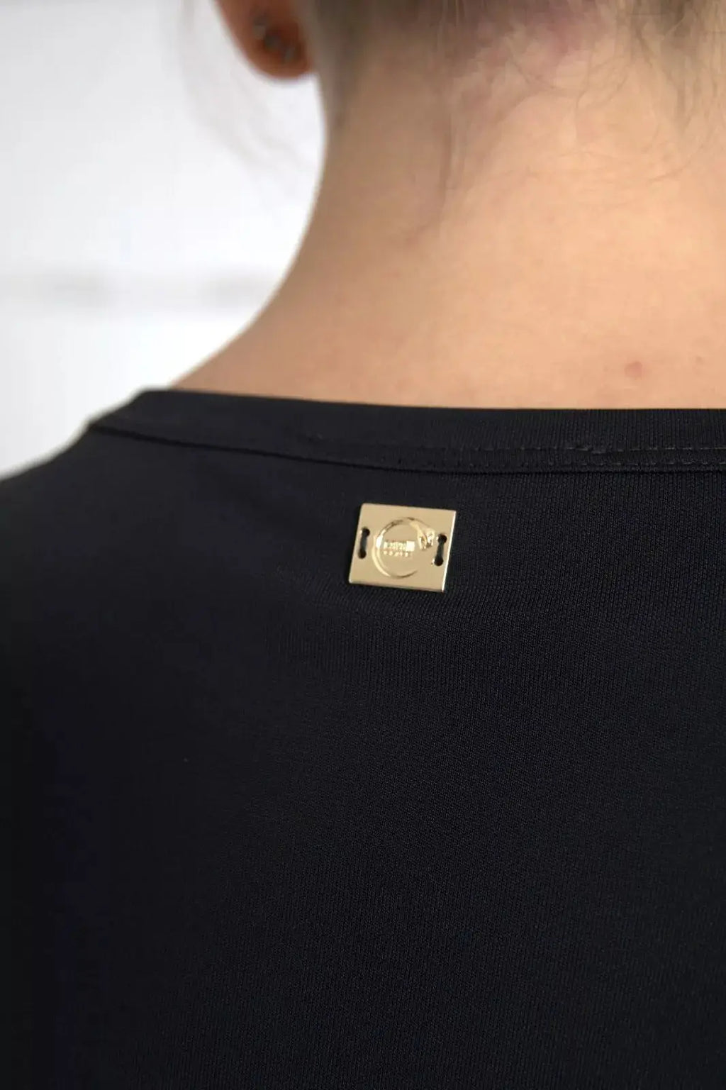 Étiquette métallique rectangulaire dorée avec logo embossé cousue sur lencolure noire en viscose du t-shirt roberto cavalli
