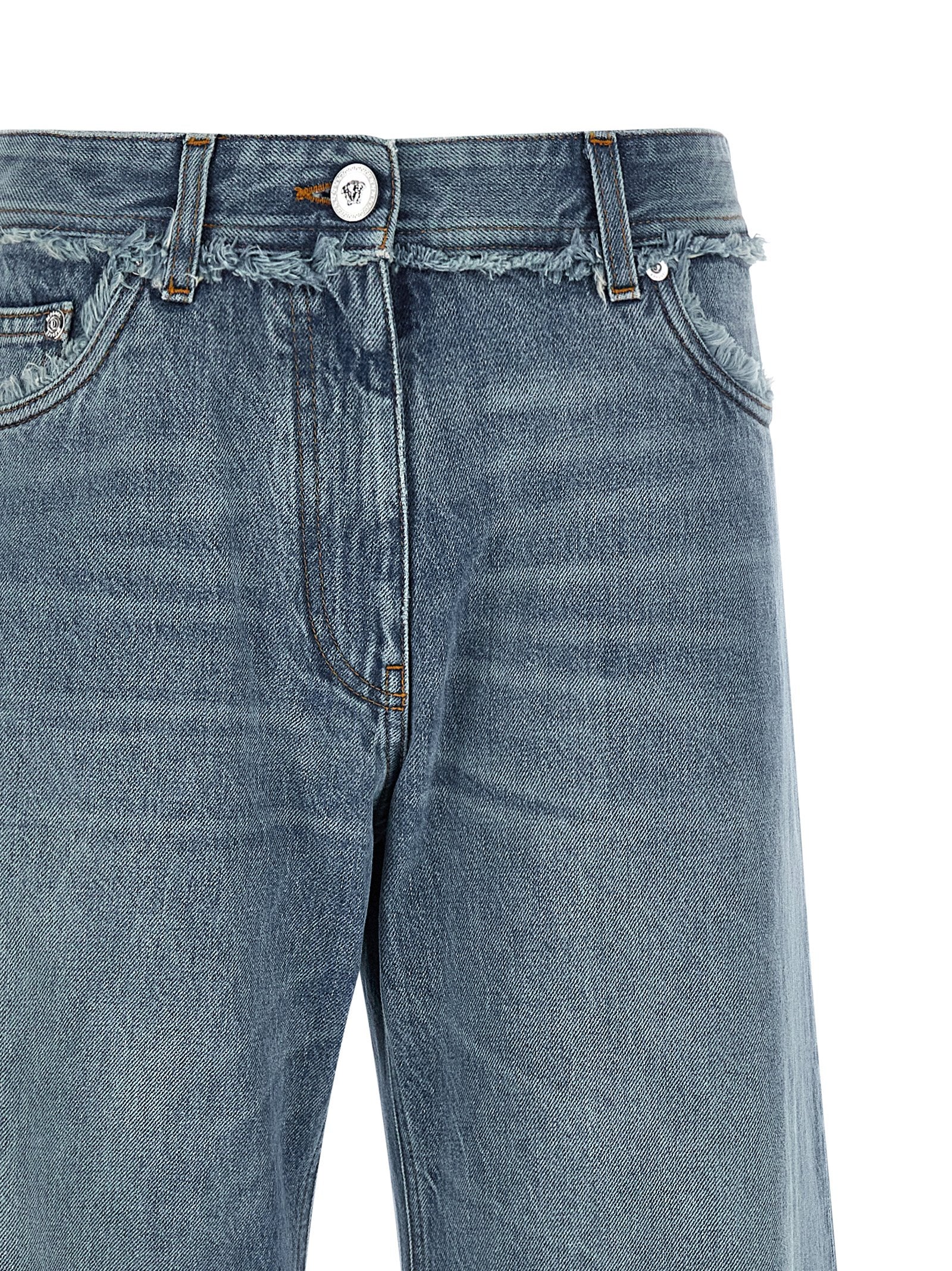 Jeans boyfriend en coton bleu Versace, coupe décontractée, détails de style et logo de la marque visibles sur le vêtement.