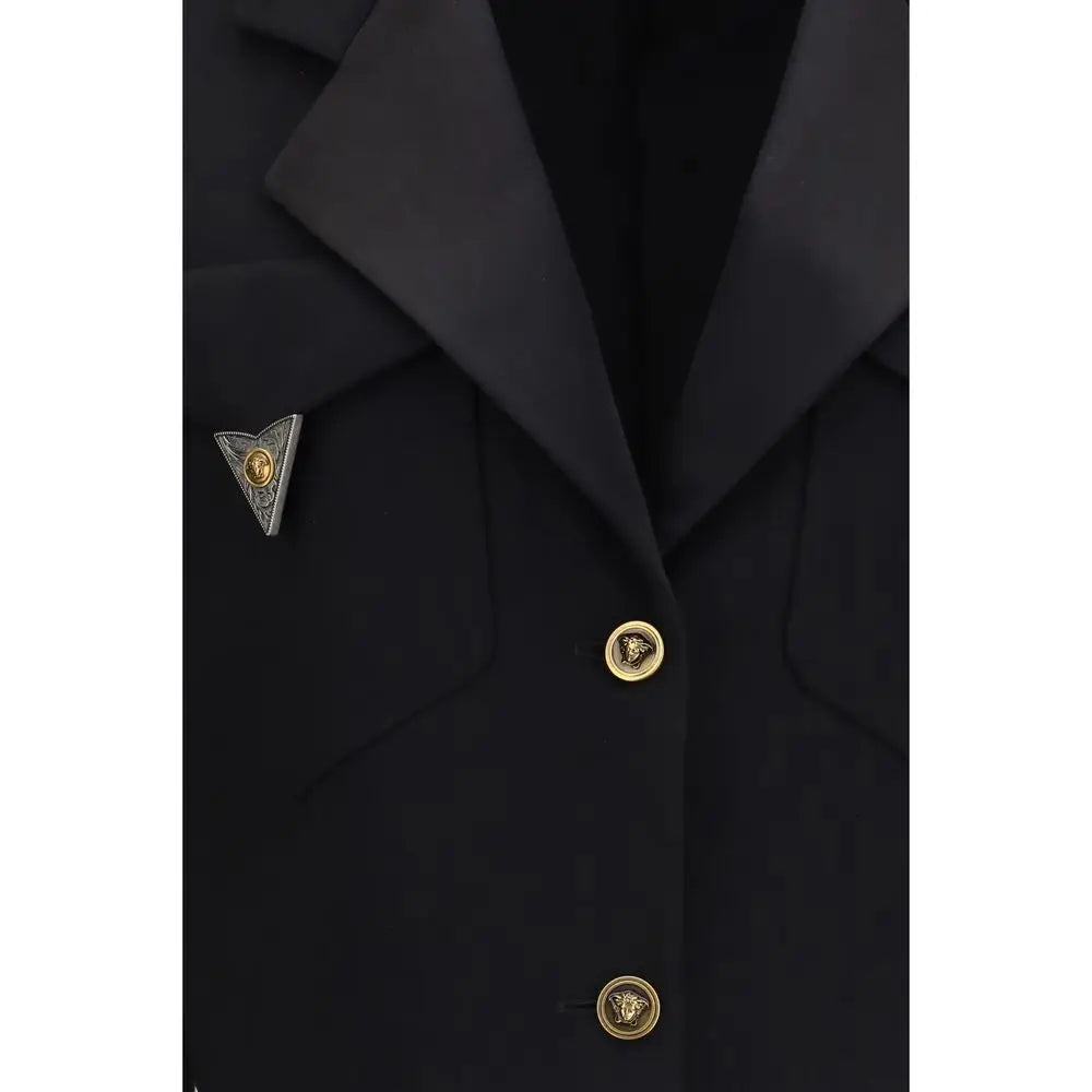 Un pin triangulaire argent avec une médaille dorée gravée au centre sur un blazer versace noir en laine oves aries