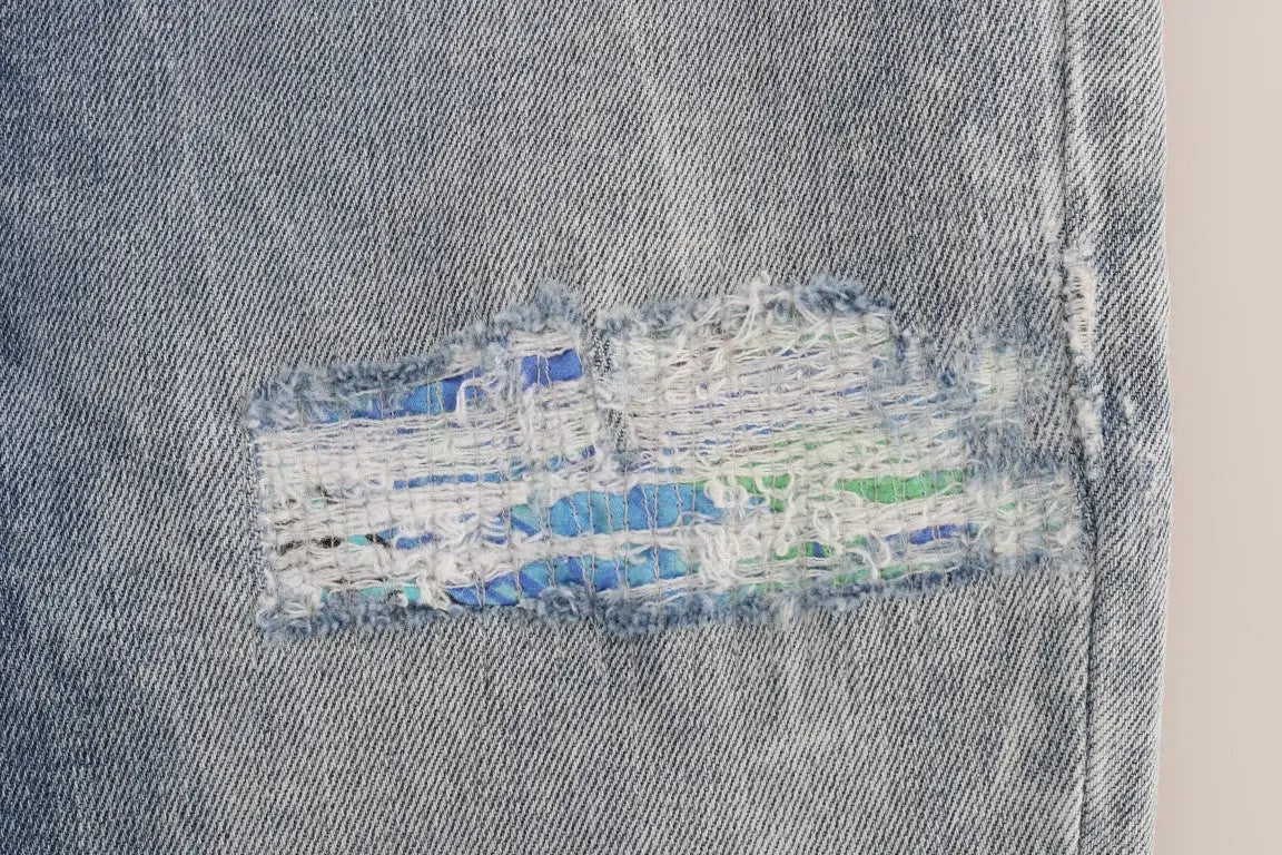 Une pièce déchirée de jean bleu délavé versace avec bord effiloché dévoilant un tissu imprimé coloré en dessous
