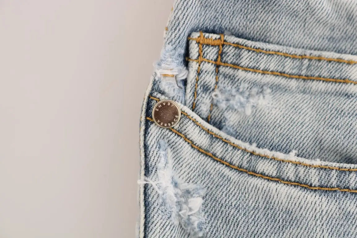 Poche arrière déchirée en jean bleu clair versace avec bouton en métal marron gravé versace sur jean slim stretch
