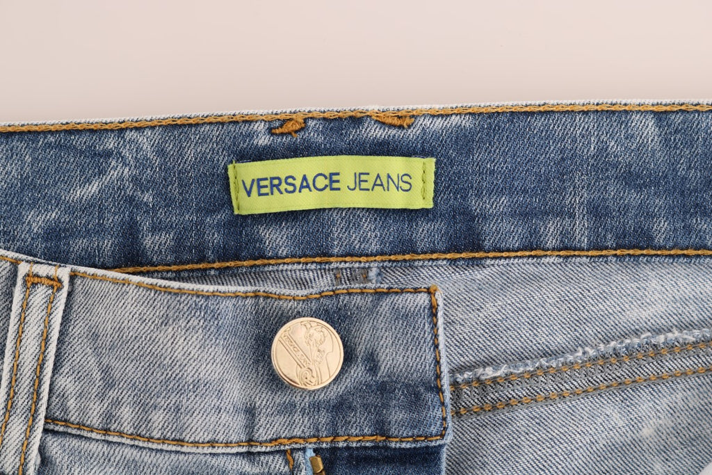 Jeans slim stretch déchirés bleu wash de Versace Jeans, coupe ajustée et tendance, visible sur l'image.