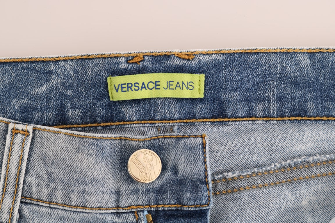 Jeans slim stretch déchirés bleu wash de Versace Jeans, coupe ajustée et tendance, visible sur l'image.