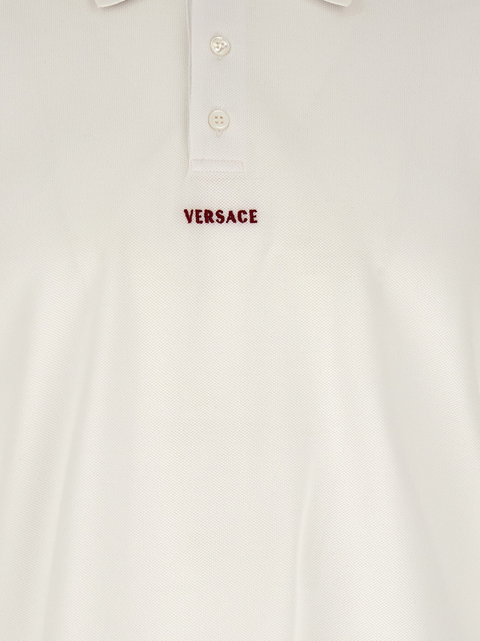 Chemise polo blanche en coton de la marque Versace, avec logo distinctif, portée sur mannequin.